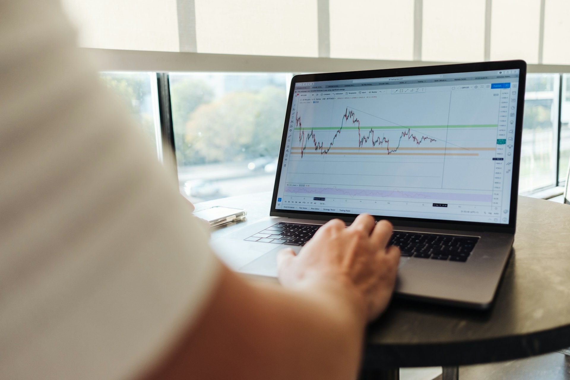 Person analysing data and market trends on a laptop using a trading chart platform.